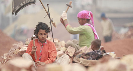 Bambini del Bangladesh rompono mattoni da usare come ghiaia nelle costruzioni a Dacca, in Bangladesh.