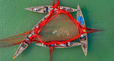 Luftaufnahme von einheimischen Fischern mit einem großen Netz im Fluss.