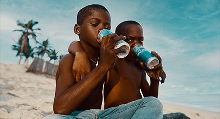 Two young African children hanging out together at the beach.