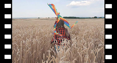 Une petite fille avec un cerf-volant court dans un champ de blé.