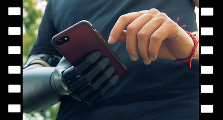 Mann mit moderner Handprothese schaut auf sein Handy. 4K.