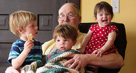 Tres niños sentados en el regazo de su abuelo