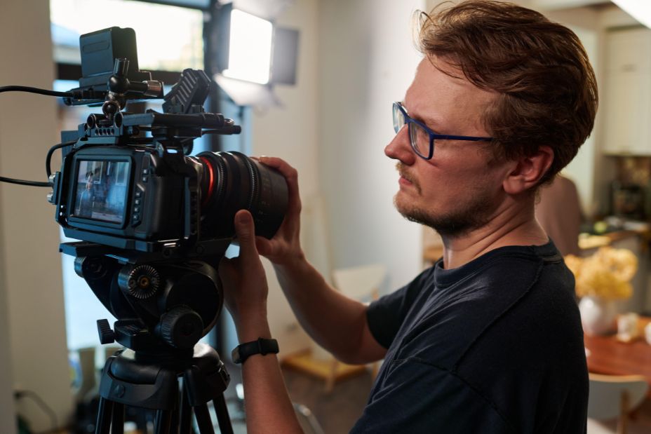 Young videographer or cameraman adjusting focus of his video camera while standing in studio and preparing for shooting advertisement - Image ID: 2J6HPCX (RF)