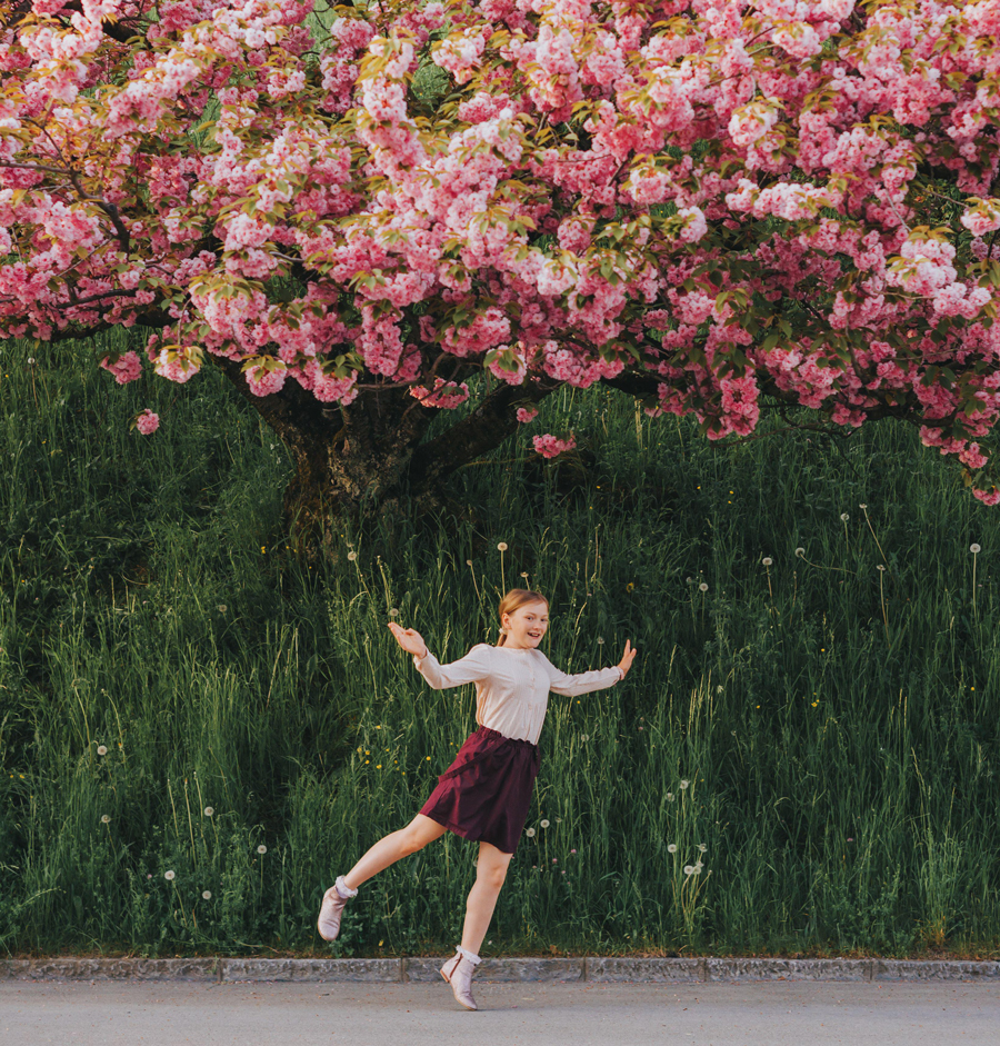 Immagine primaverile di un ciliegio in fiore, con una bambina che gioca sotto un ciliegio