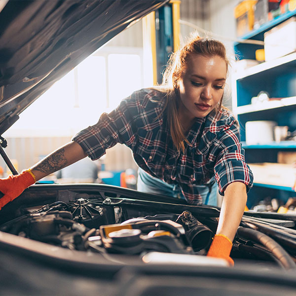 Destroying gender stereotypes. Young woman auto mechanic working at auto service station using different work tools. Gender equality. Work, occupation