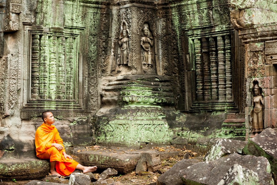 Monk sitting in an ancient temple with carvings