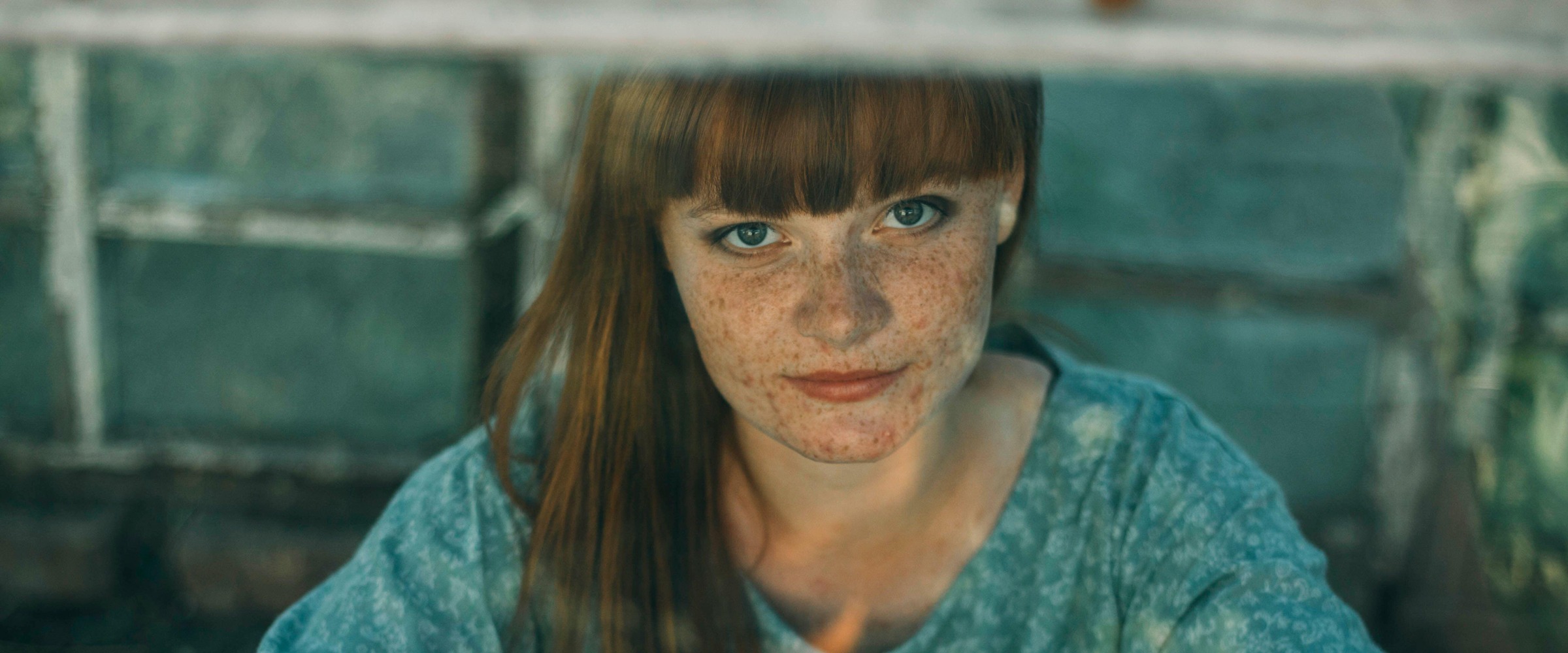 Jeune femme avec des taches de rousseur regardant par la fenêtre