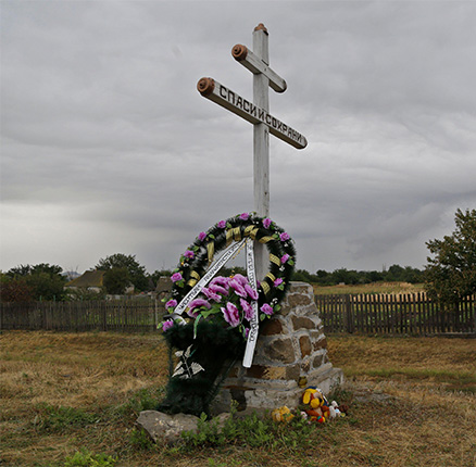 A commemorative wreath is laid at the foot of a cross, near the wreckage of Malaysia Airlines Flight 17 plane seen outside the village of Hrabove, eastern Ukraine, Tuesday, Sept. 9, 2014.