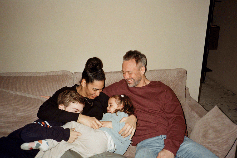 Padre e madre trascorrono il tempo libero con i bambini seduti sul divano a casa