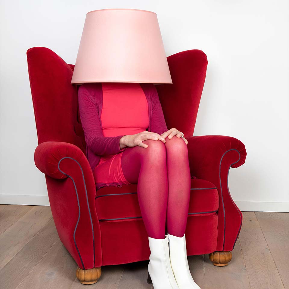 Donna seduta sulla poltrona mentre il viso coperto con paralume