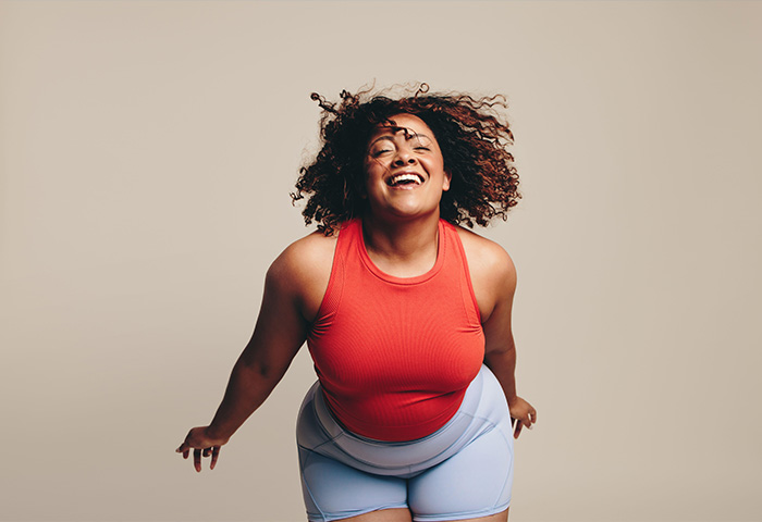 Fit and curvy woman having a blast in a dance workout, a lively and expressive physical activity. Woman celebrating her body, flaunting her confidence