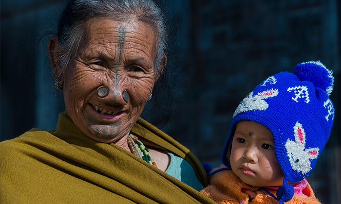 Apatani woman with facial tattoos and traditional nose plugs / Yapin Hulo holding baby. 