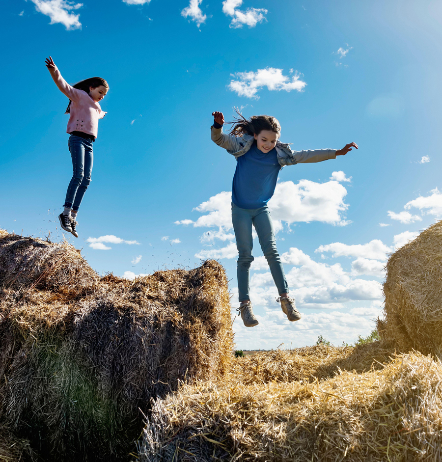 Due giovani sorelle giocano su un mucchio di balle di fieno
