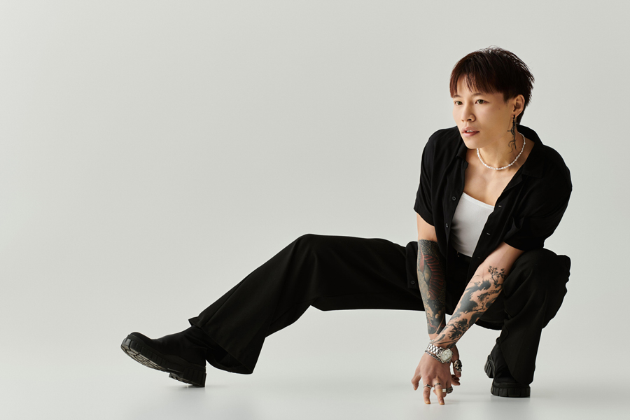 A young handsome Asian man strikes a dynamic pose in a clean, minimalist studio space