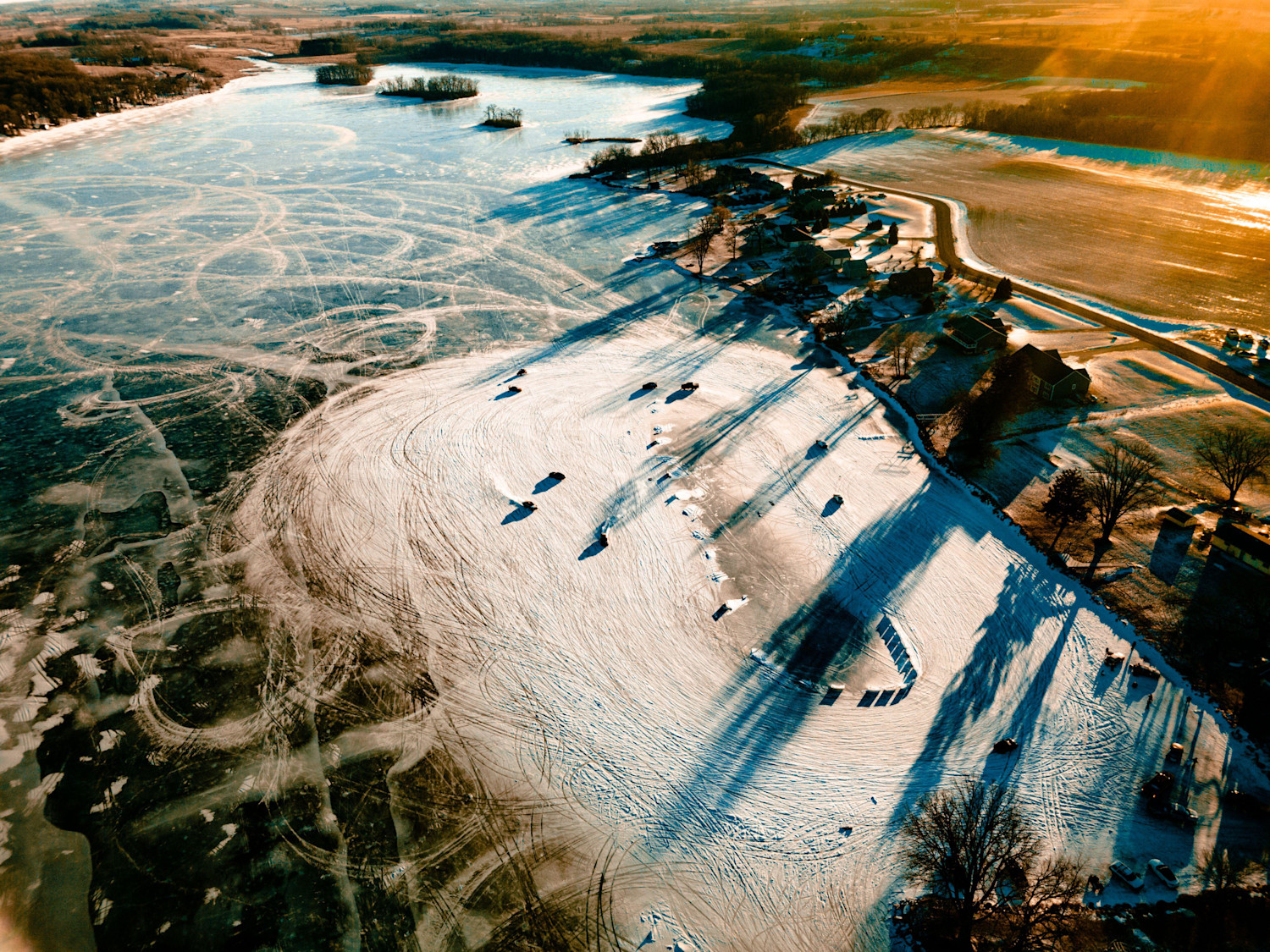 An aerial shot of a frozen lake with cars drifting on it