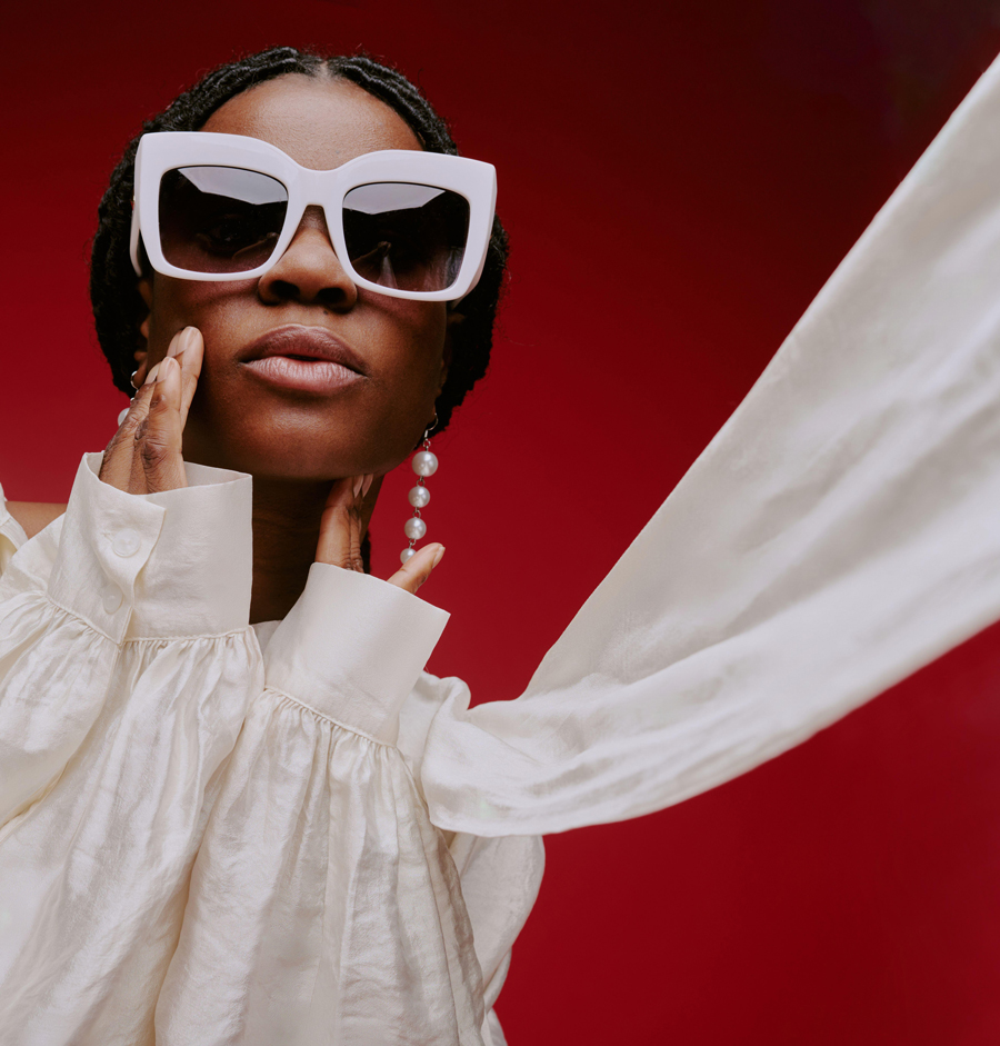 Portrait of fashionable woman posing with large sunglasses, wearing elegant white outfit