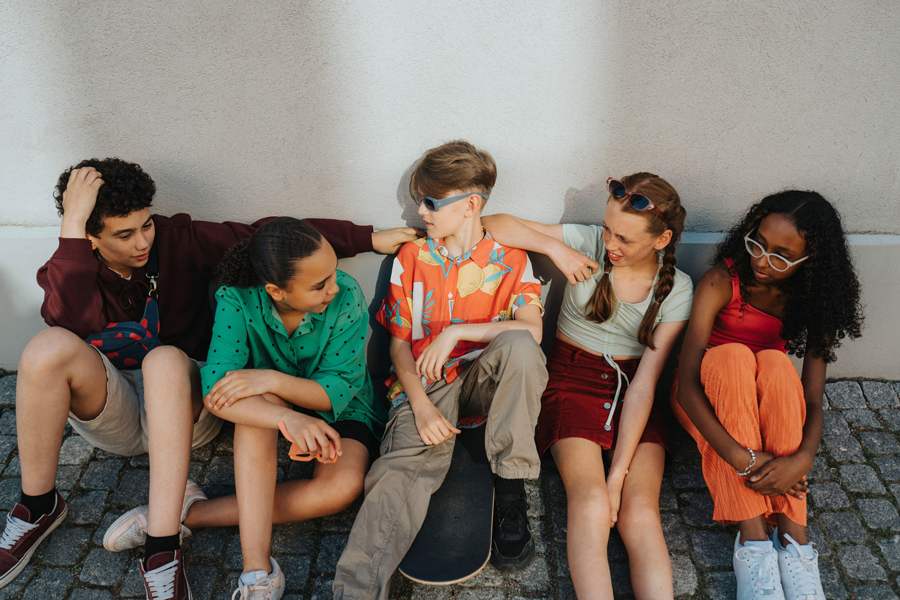 High angle view of friends sitting on ground against wall