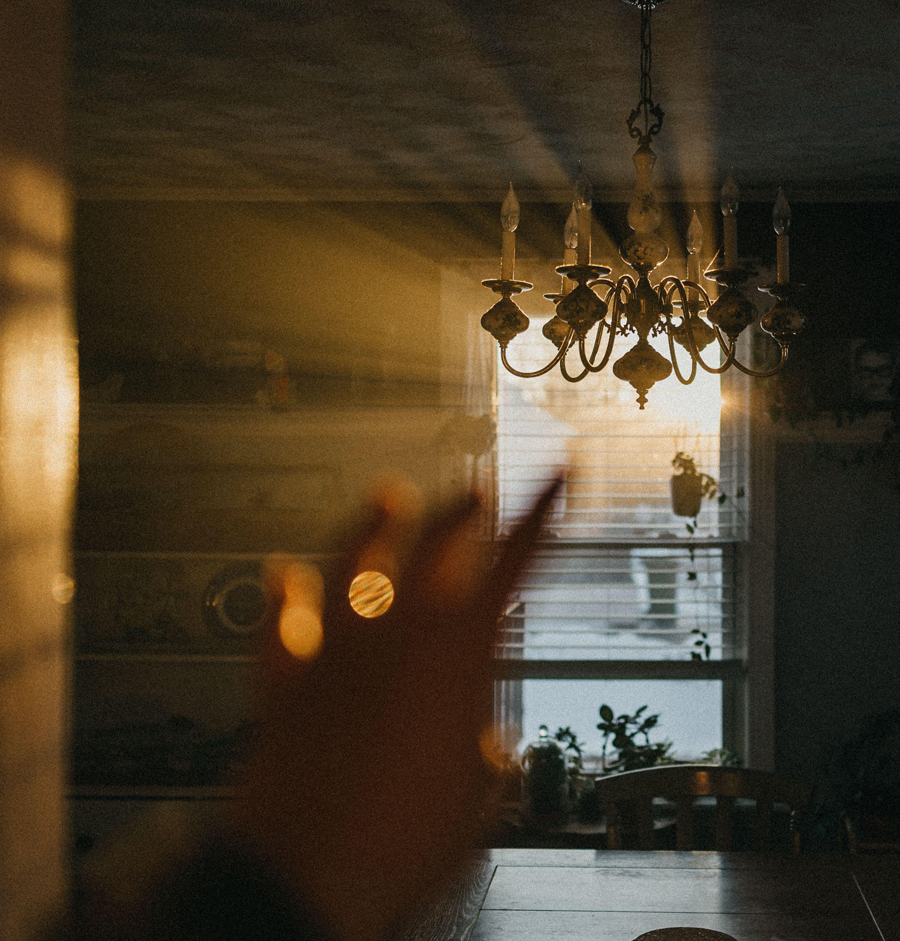 mano protesa verso il sole che filtra attraverso il lampadario