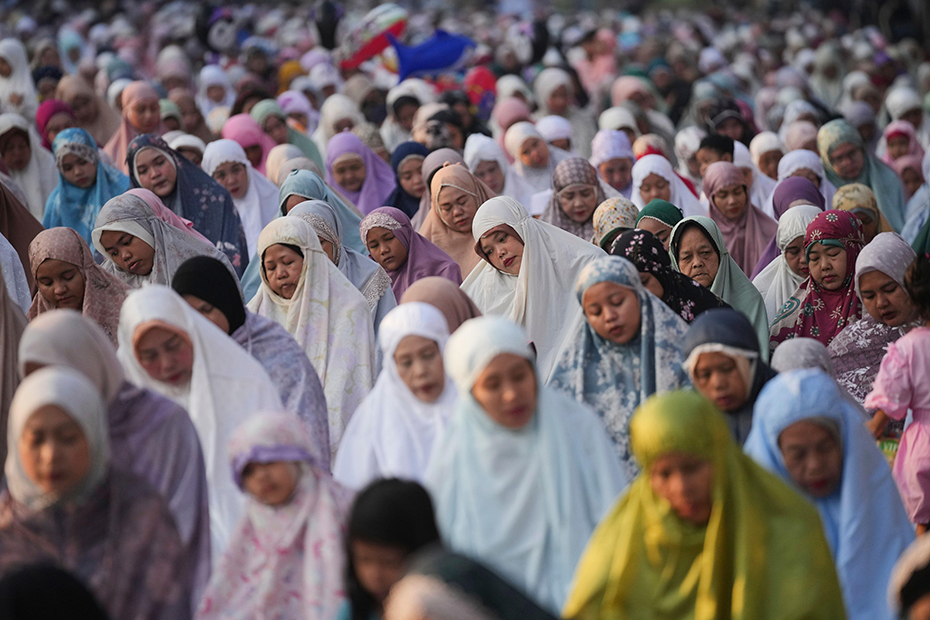 Muslim women perform morning prayer marking the Eid al-Adha holiday on a street in Jakarta, Indonesia