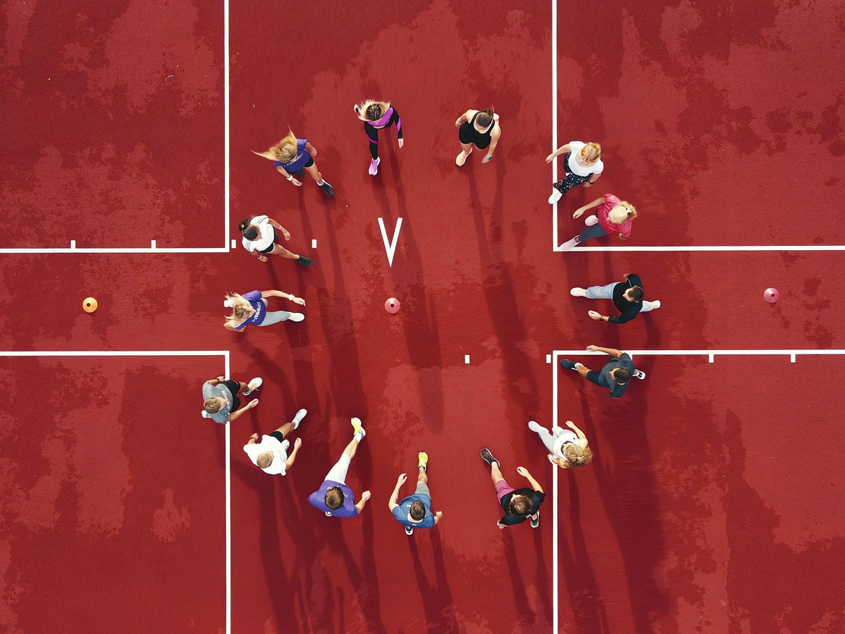 A high-angle view of a group of people playing a team sport on a bright red court.