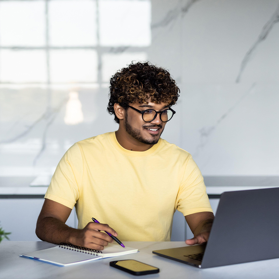 Excited indian man student working online from home, remote job