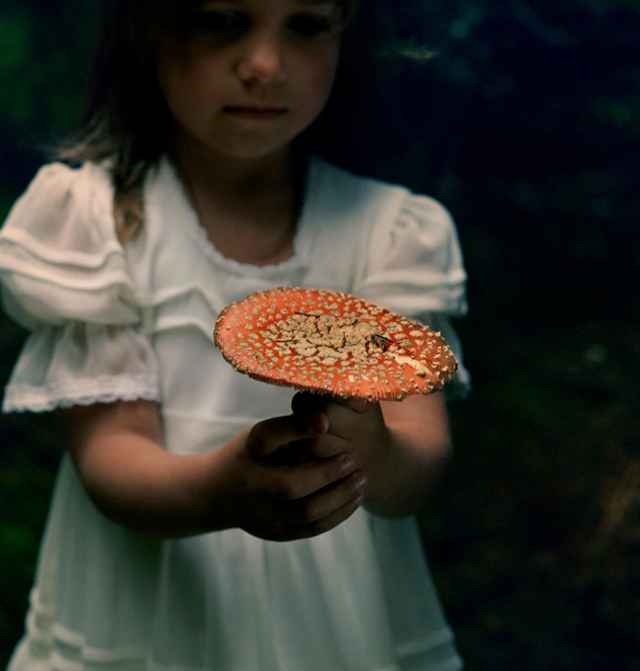 Fille caucasienne tenant un champignon dans la forêt