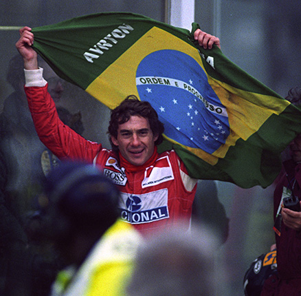 Brazilian Ayrton Senna flying the Brazilian flag as he works his way through the crowd to the winners podium after victory in the European Grand Prix at Donnington Park. 