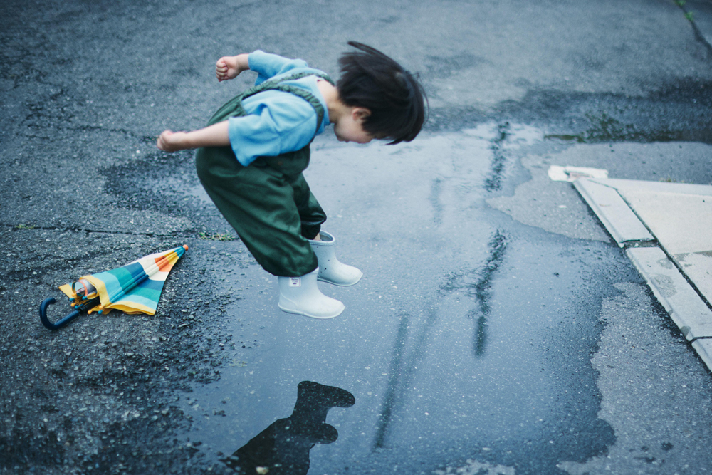 Japanese kid playing outside on a rainy day