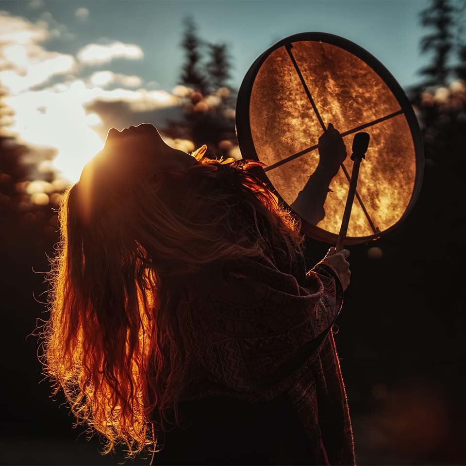 Bella ragazza sciamanica suona il tamburo sciamanico nella natura. 