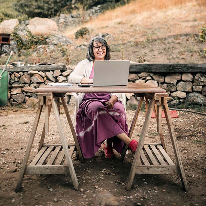 Campingfrau sitzt am Tisch und benutzt einen Laptop.