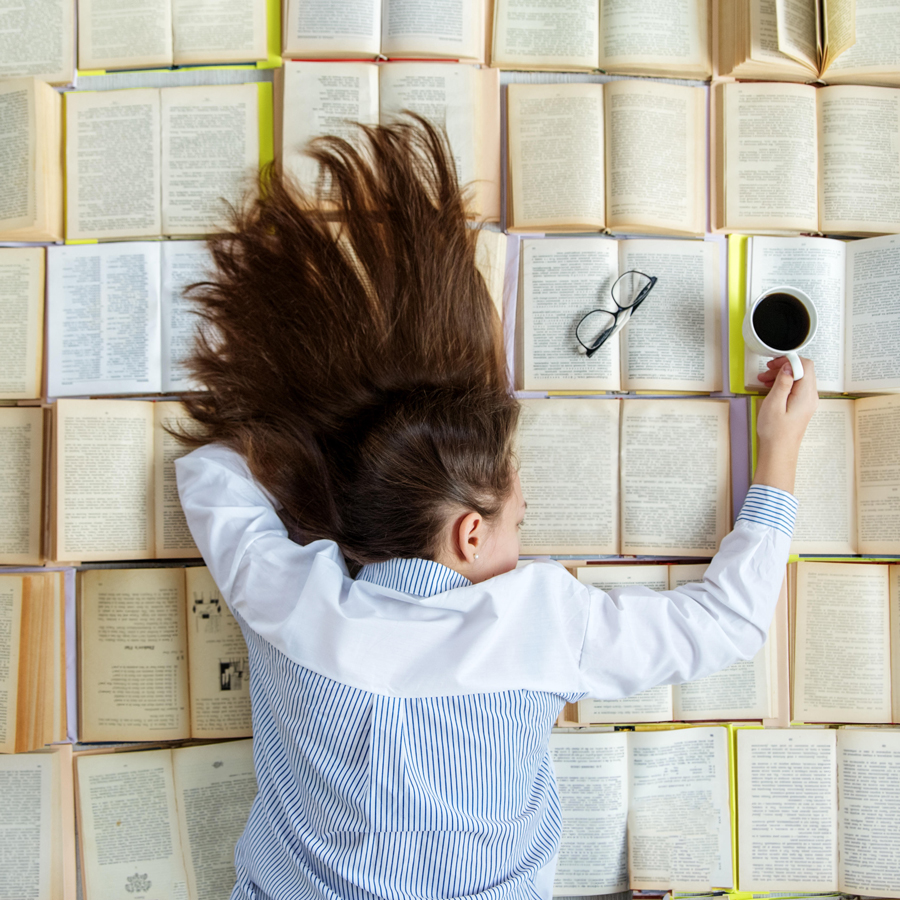 A young girl is preparing for exams and has a lot of books open