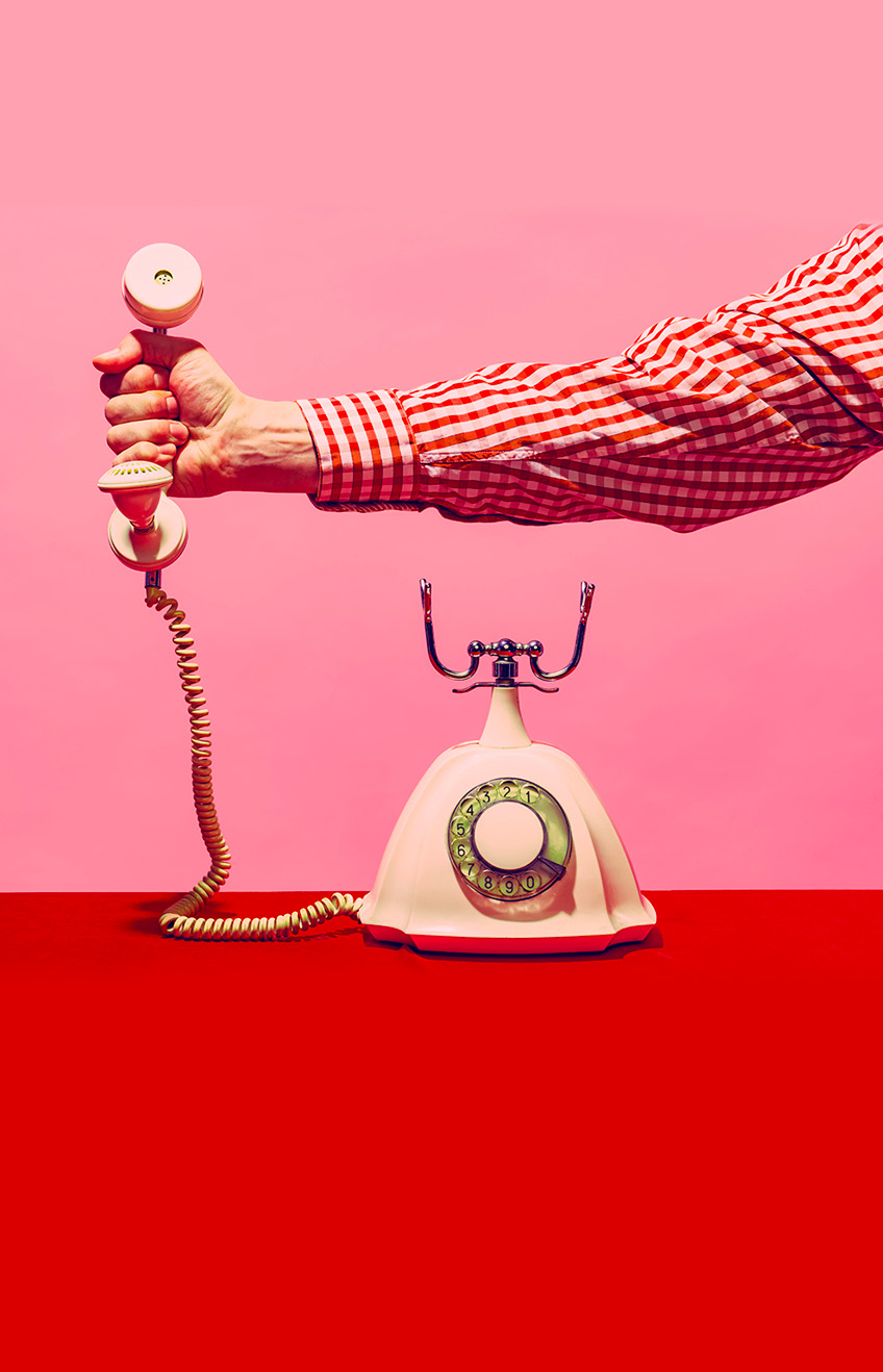 2J2X2GP - Pop art photography. Retro objects, gadgets. Female hand holding handset of vintage phone isolated on pink and red background. Vintage, retro fashion