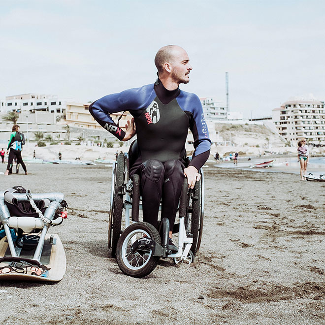 Kitesurfer maschile disabile in muta da sub sulla spiaggia di Tenerife, Isole Canarie, Spagna.