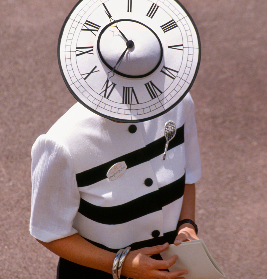 Ein Besucher der Pferderennveranstaltung „Royal Ascot“ auf der Pferderennbahn von Ascot in Berkshire im Jahr 1995, der einen Hut in Form eines Zifferblatts trägt