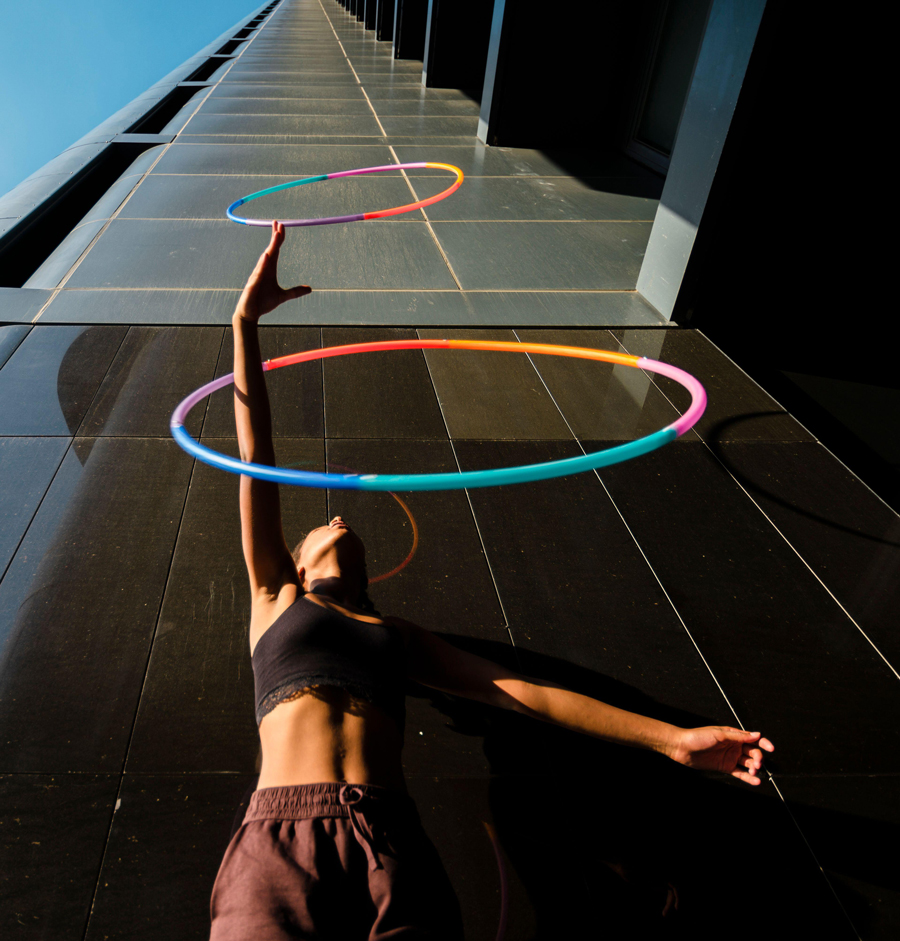 Donna sportiva che fa il giocoliere con cerchi di plastica fuori da un edificio per uffici