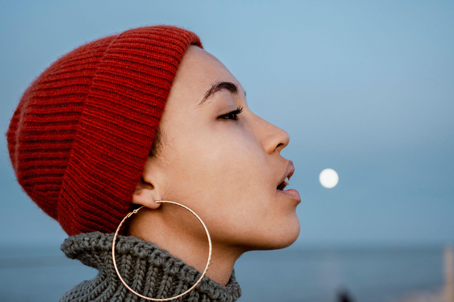 Young woman looking away while sitting with mouth open against sky