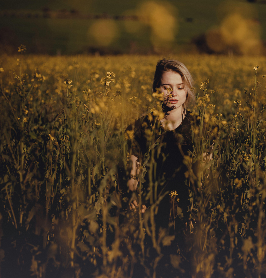 Donna in campagna con gli occhi chiusi tra i fiori