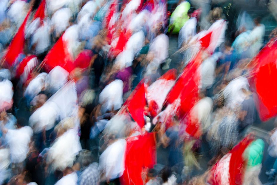 Blurry people in street protest walking with red flags, from above - Image ID: K9JN5R (RF)