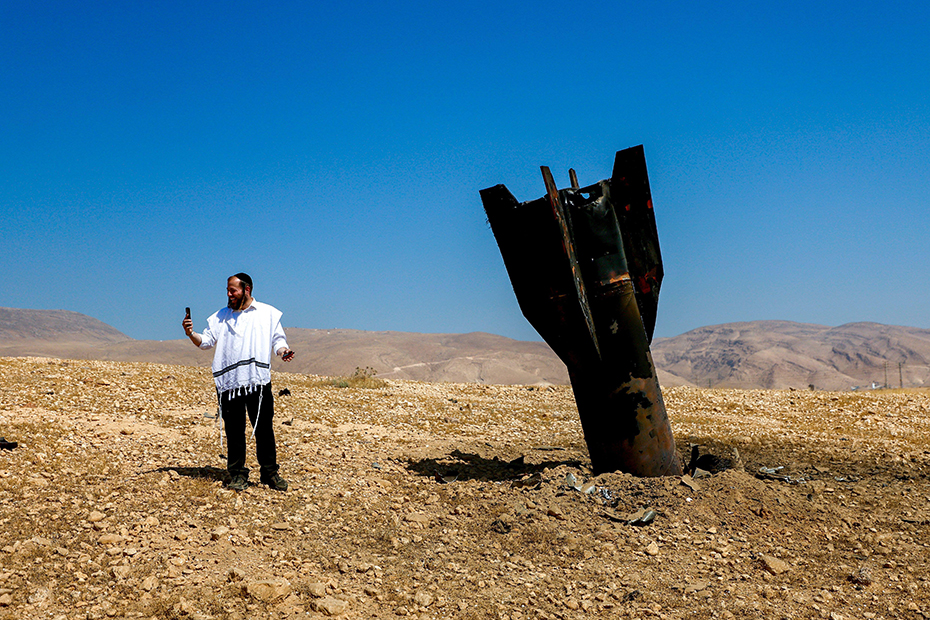 An Israeli Ultra-Orthodox Jewish man takes a selfie with the wreckage of a missile protruding from the ground, following an Iranian strike near the West Bank city of Jericho. 