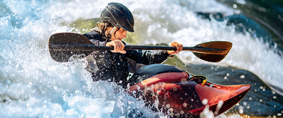 Banner kayak sulle rapide, rafting sport estremo. Un ragazzo in kayak naviga su un fiume di montagna.