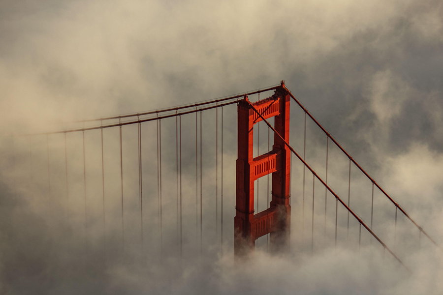 Aerial view of Golden Gate Bridge piercing through a sea of ethereal fog