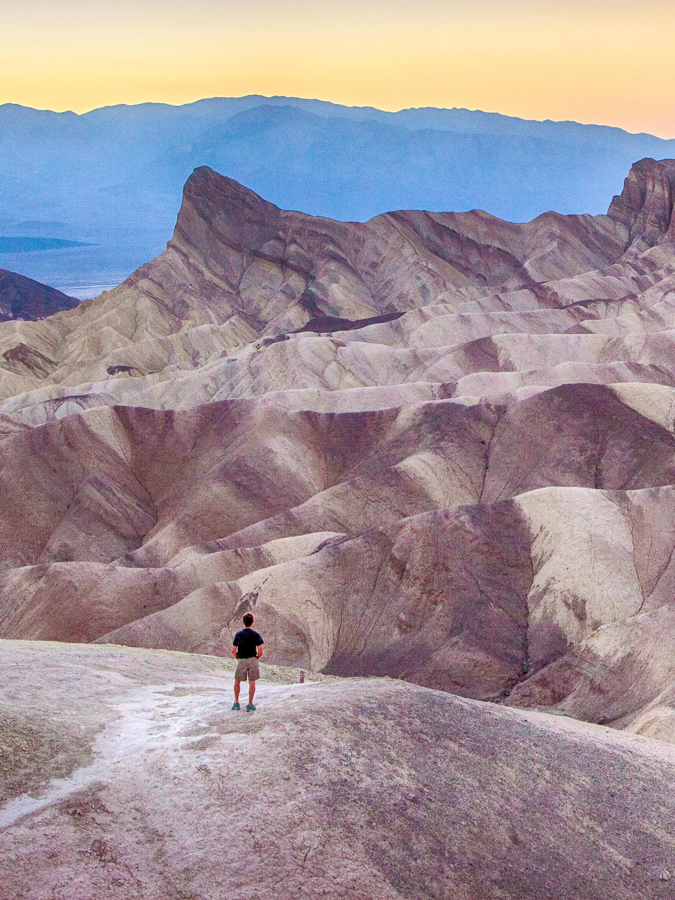 View of man enjoying sunset at famous Zabriskie Point in beautiful golden evening light in summer, Death Valley National Park, California