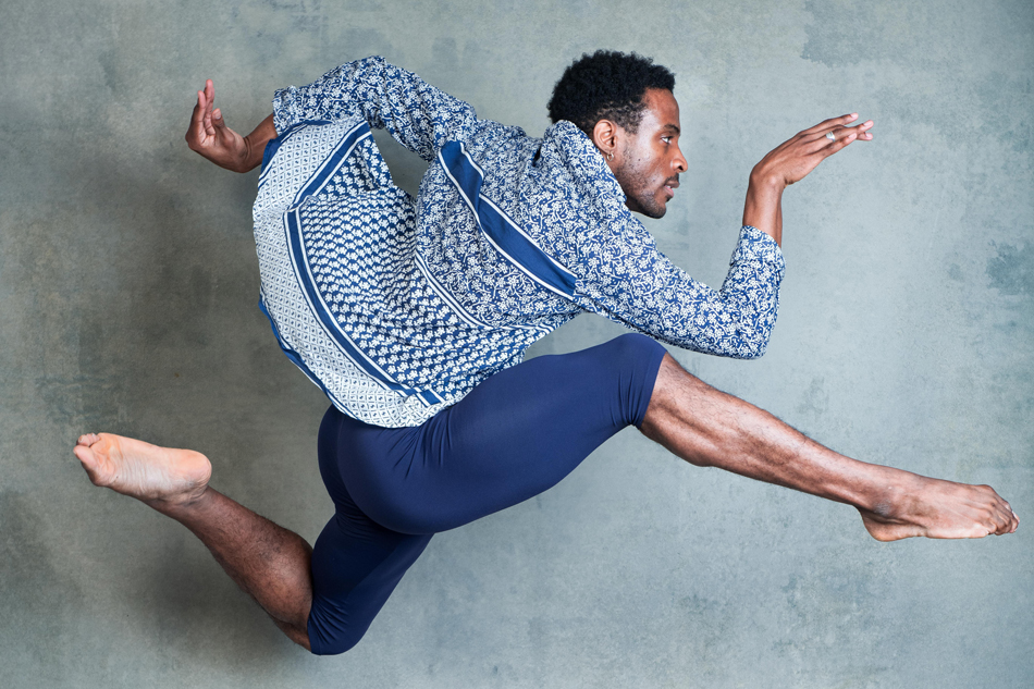 Black male dancer with toned bare chest in dance movement in studio