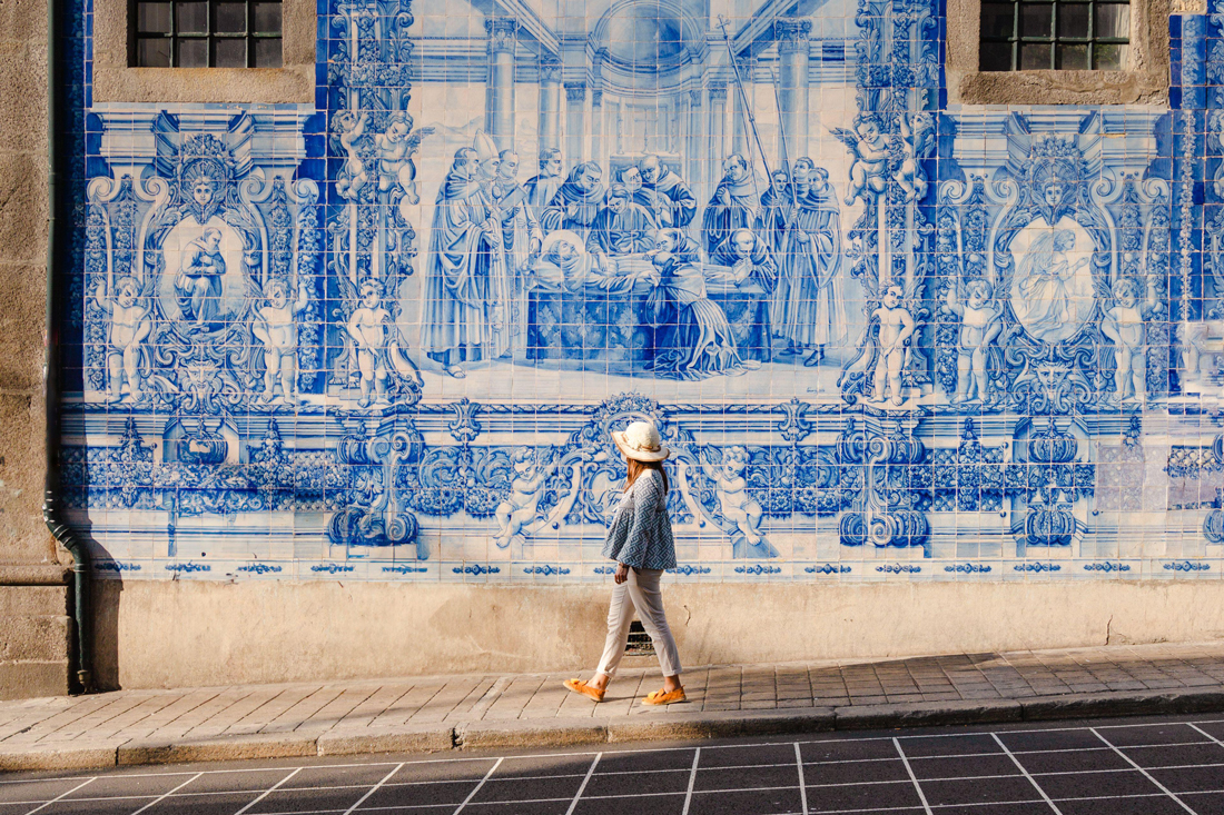 Tourist walking infront of blue tiles on walls, Porto, Portugal