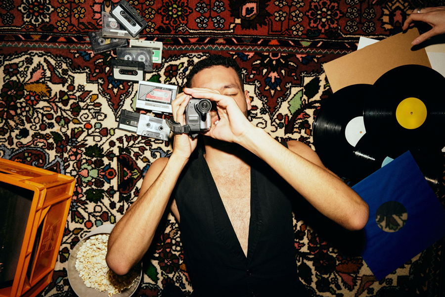 Directly above shot of young man filming through video camera while lying on carpet amidst music equipment at home