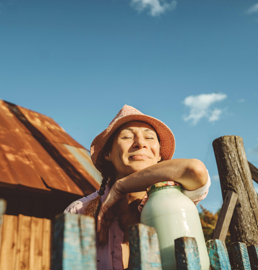 Donna sorridente con gli occhi chiusi appoggiata al barattolo di latte