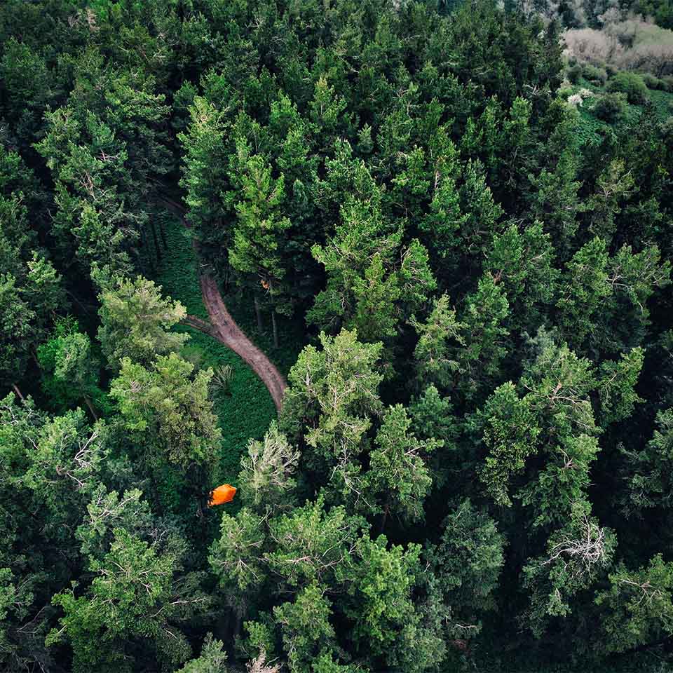 Vue aérienne d’une tente orange dans une forêt en montagne. Photo prise par un drone.