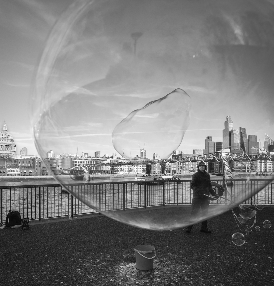 A black and white image of a giant bubble artist on the South Bank in London