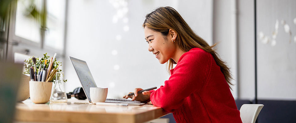 Giovane donna seduta a una scrivania mentre lavora su un laptop