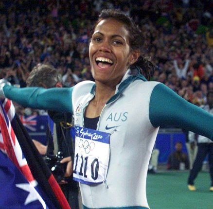 Australia's Cathy Freeman carries both the Aboriginal and the Australian flags during a victory lap after winning the women's 400m final at the Sydney Olympic Games September 25, 2000.